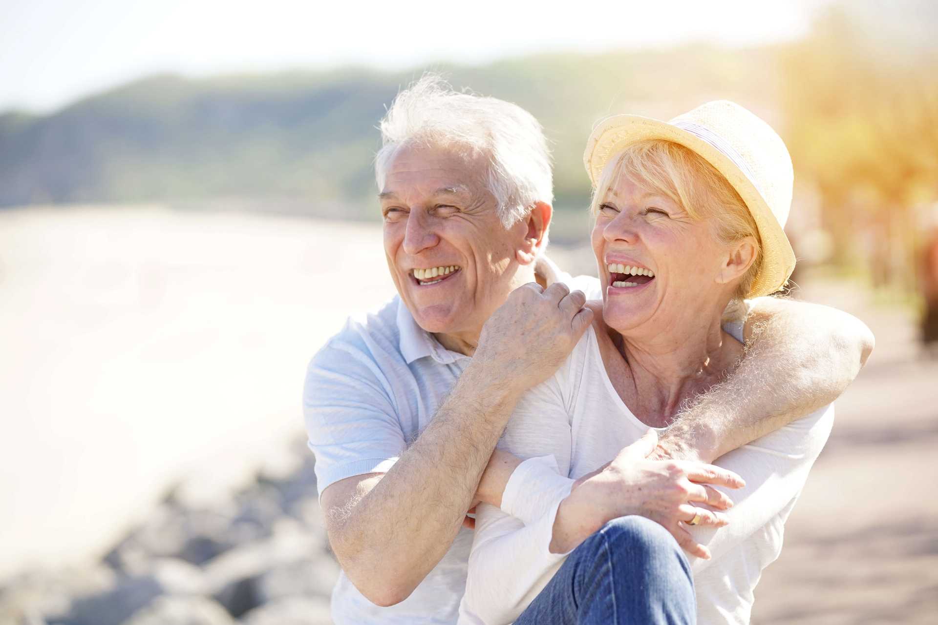 Eldre par slapper av ved havet på en solrik dag